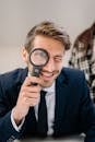 Man in Blue Suit Holding Magnifying Glass