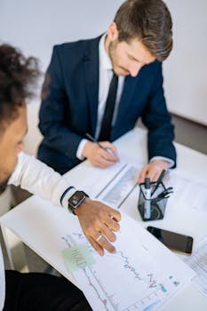 Two businessmen analyzing stock charts and statistics during a meeting.