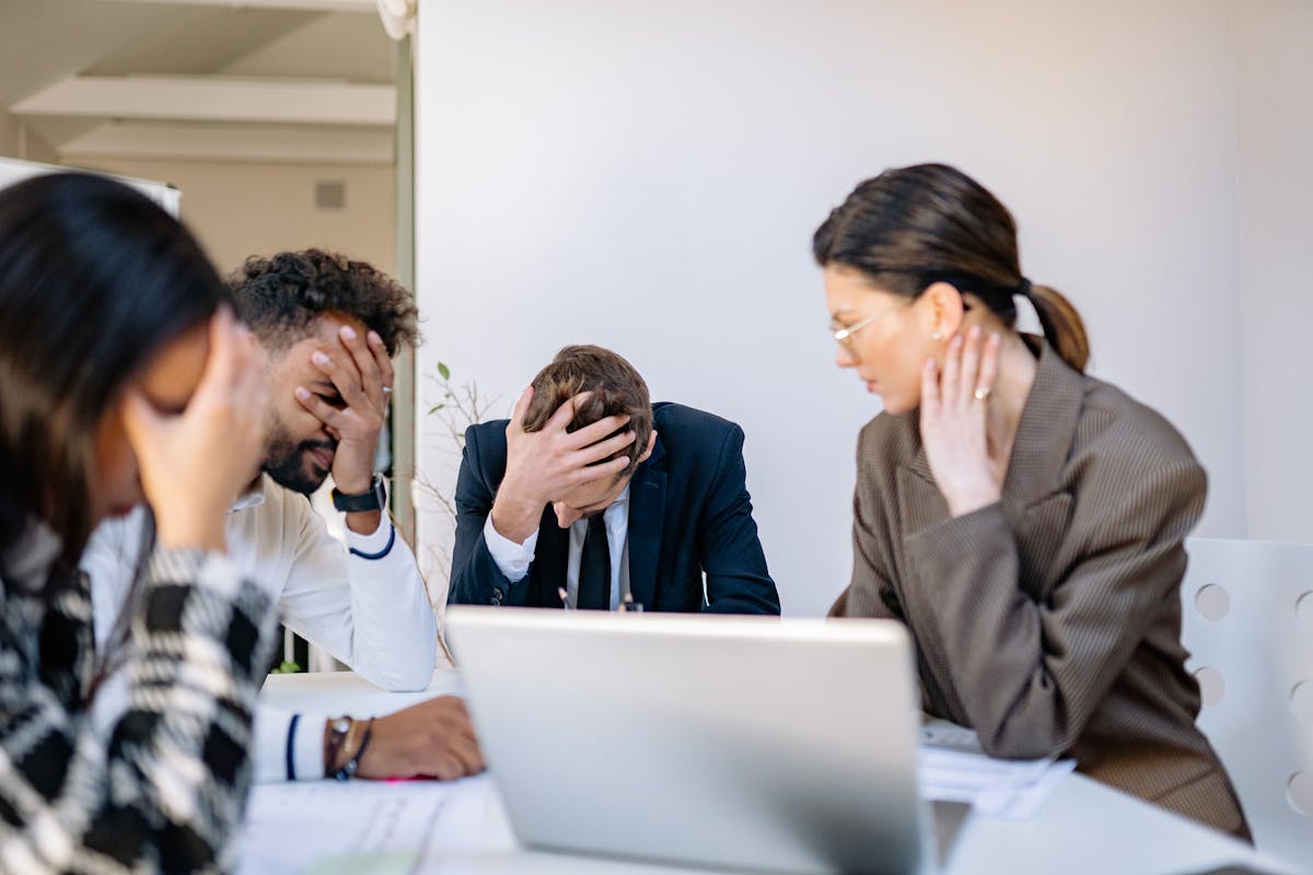Persone d'ufficio in abiti formali appaiono stressate durante una riunione