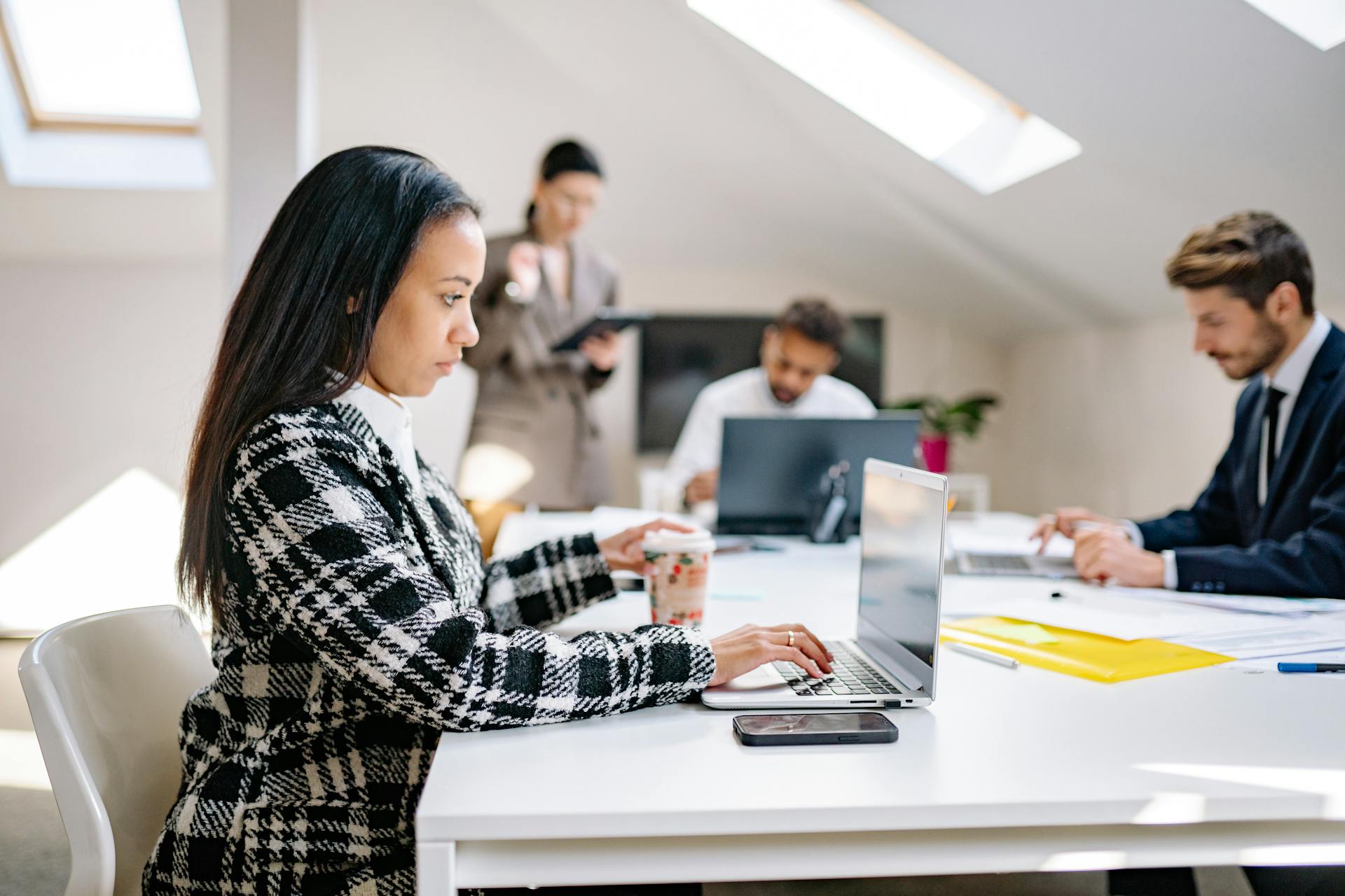 Business professionals working in a modern, collaborative office environment with laptops.