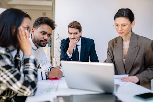 Free Focused team of professionals discussing work at a laptop during an office meeting. Stock Photo
