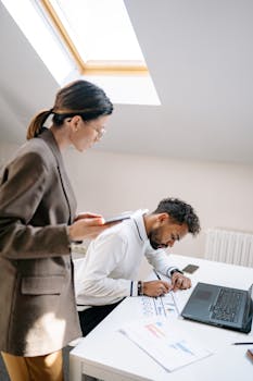 Two business professionals working on documents at an office desk.