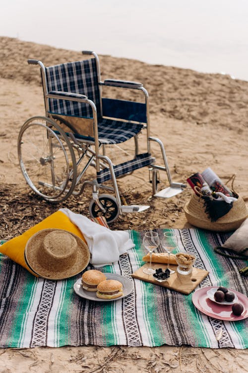 A Picnic Set-up Beside Wheelchair on a Sandy Shore