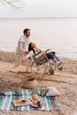 Man in White Dress Shirt and Blue Denim Jeans Standing Beside Black and Brown Stroller