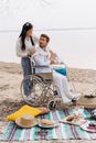Man and Woman Sitting on Blue and Yellow Chair on Beach