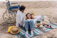 Couple Sitting on Green and Blue Mat on Beach