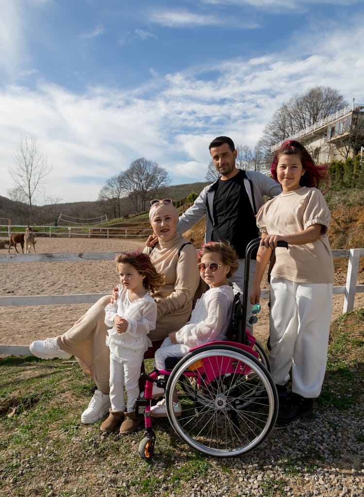 Positive Family With Girl In Wheelchair In Sunny Park