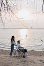Woman in White Long Sleeve Shirt Sitting on Black Wheelchair Near Sea