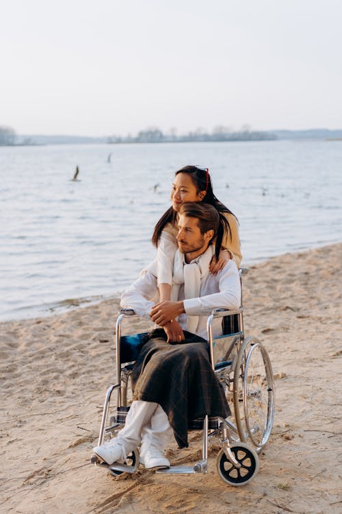 Kobieta W Białej Koszuli Z Długim Rękawem Siedzi Na Niebieskim Wózku Inwalidzkim Na Plaży