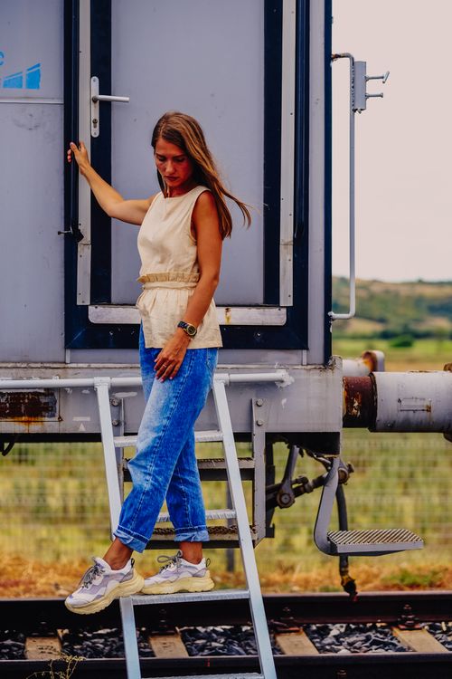 Free Woman in casual attire standing on train stairs with a scenic outdoor background. Stock Photo