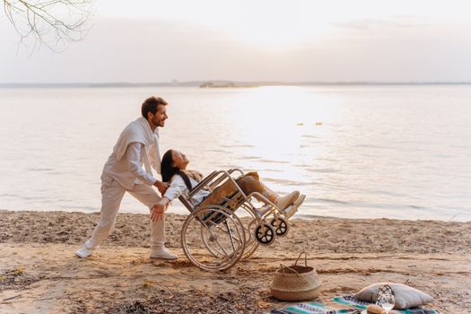 Couple enjoying a sunny day at the beach, with one person in a wheelchair.