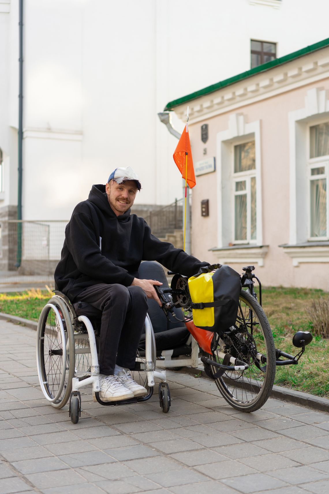 Wheelchair user beside an adaptive cycle on an urban pathway