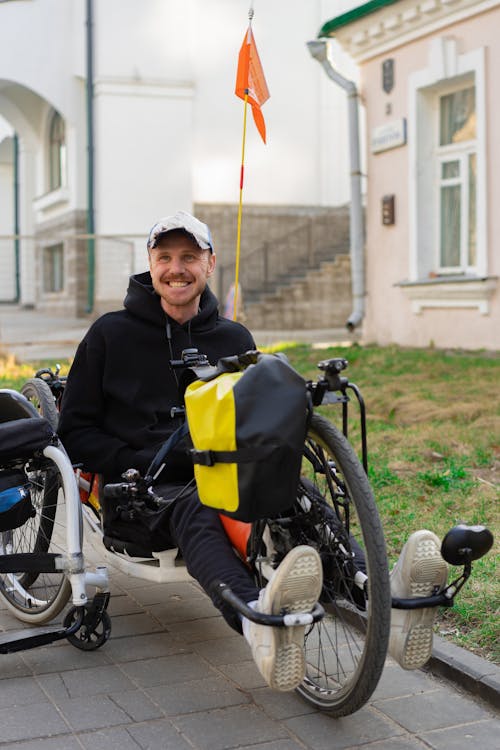 Man in Black Jacket Riding on a Recumbent Bike Attached to Wheelchair