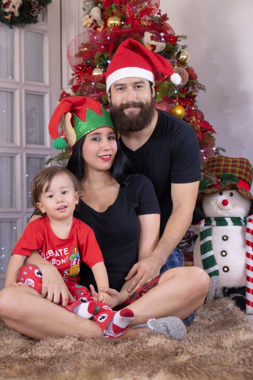 Free Happy family in Santa hats celebrating Christmas by the tree. Stock Photo