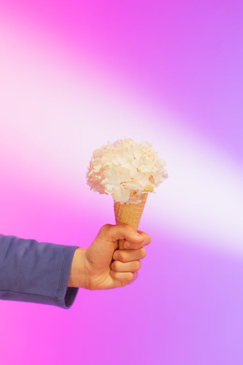 Person Holding an Ice Cream Cone on a Purple Background 