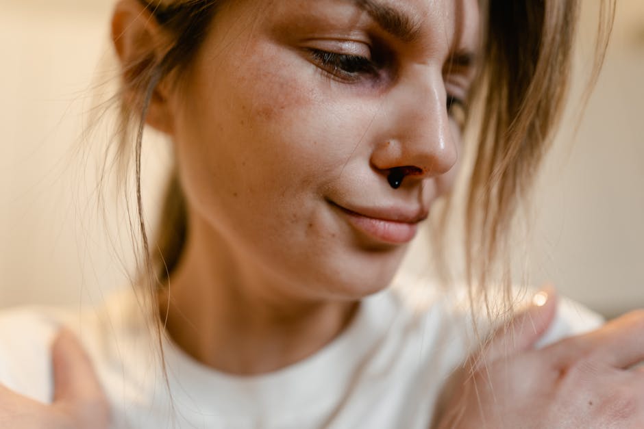 Emotionally intense close-up portrait of a woman with a nose injury, depicting vulnerability.