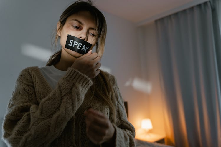 A Woman Removing The Black Tape On Her Lips