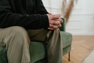 Person in Black Long Sleeve Shirt and Gray Pants Sitting on Green Couch