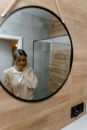 Woman in White Coat Standing Beside Round Mirror