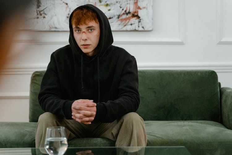 A Man In Black Hoodie Sitting On The Couch