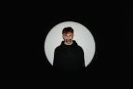 Man in Black Jacket Standing Beside White Round Wall