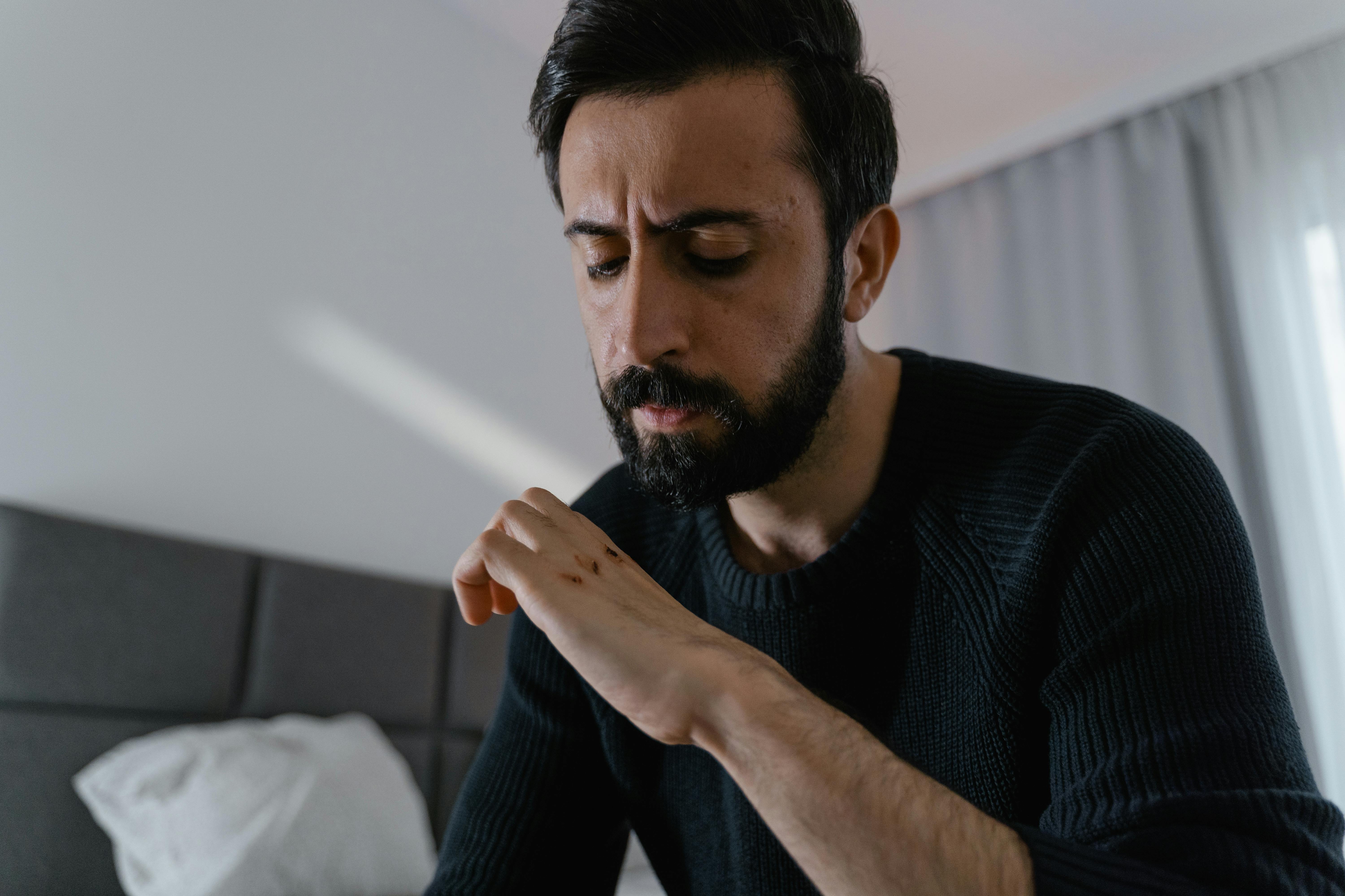 bearded man looking at the wounds on his knuckles