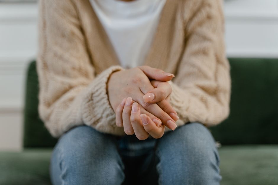 A cozy close-up of a woman's hands placed together, showcasing a knitted sweater.