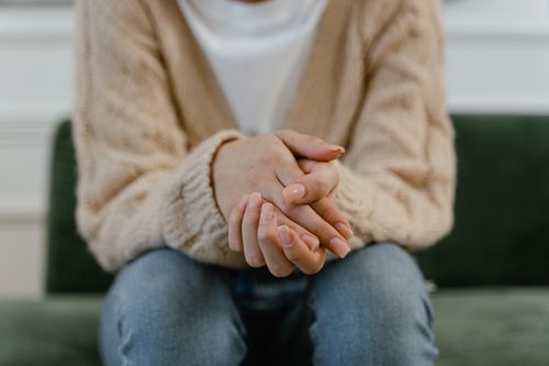 Free A cozy close-up of a woman's hands placed together, showcasing a knitted sweater. Stock Photo