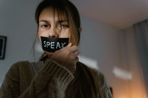 Free A woman with 'SPEAK' taped over her mouth, symbolizing silence and oppression. Stock Photo