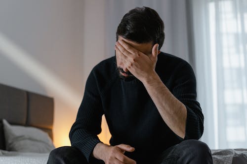 Man in Black Sweater Sitting on Bed