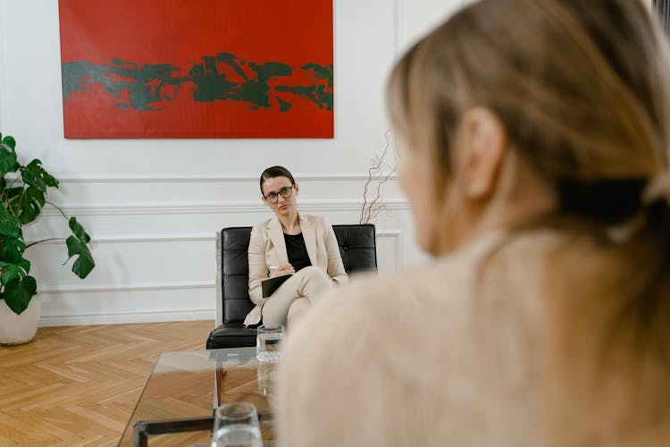 A Woman Wearing Beige Blazer Sitting On A Leather Chair