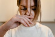 Woman in White Shirt with Hand Over Lips
