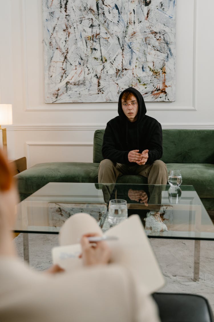 A Man In Black Hoodie Sitting On The Couch