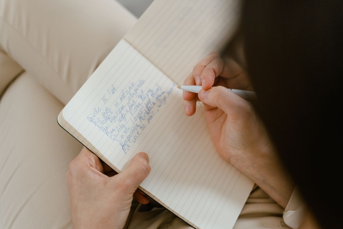 A Person Writing on a Notebook · Free Stock Photo