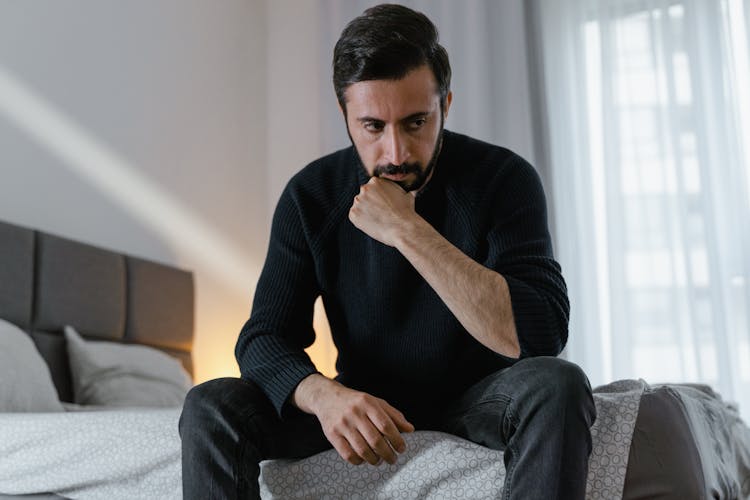 Man Sitting On The Bed While Thinking 