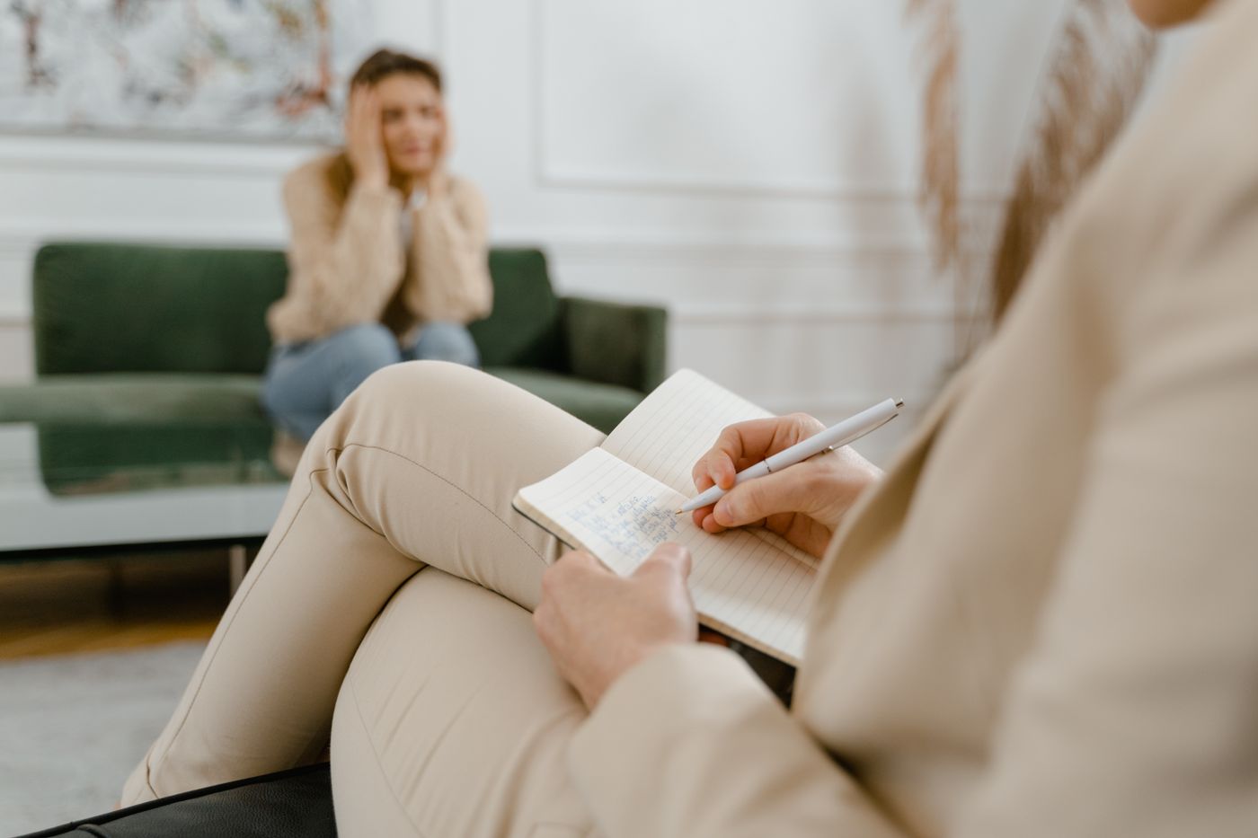 Therapist taking notes while an adult patient discusses anxiety symptoms during a mental health consultation