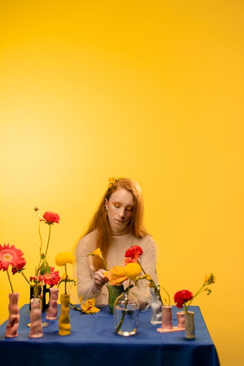 Girl in a Brown Top Sitting Near Vases with Flowers