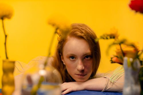 Free Artistic portrait of a woman surrounded by yellow flowers in a studio setting. Stock Photo