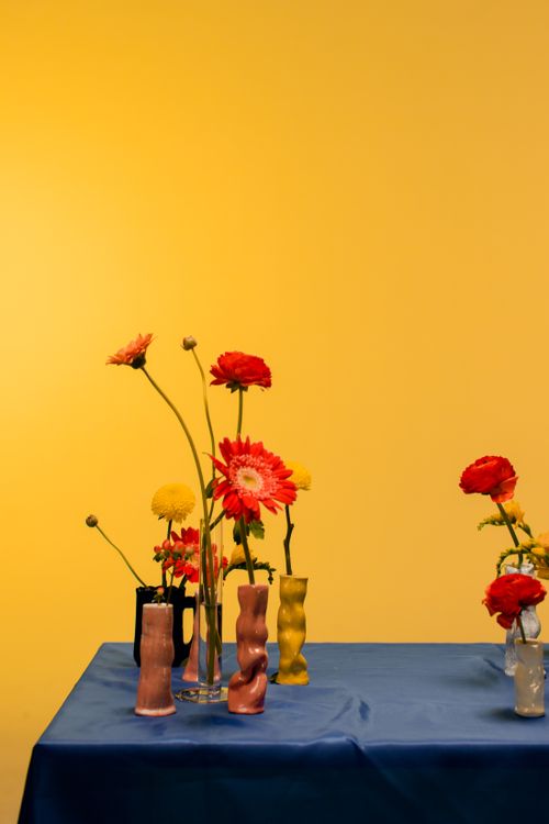 Free A striking floral arrangement with colorful flowers in unique vases against a bold yellow background. Stock Photo