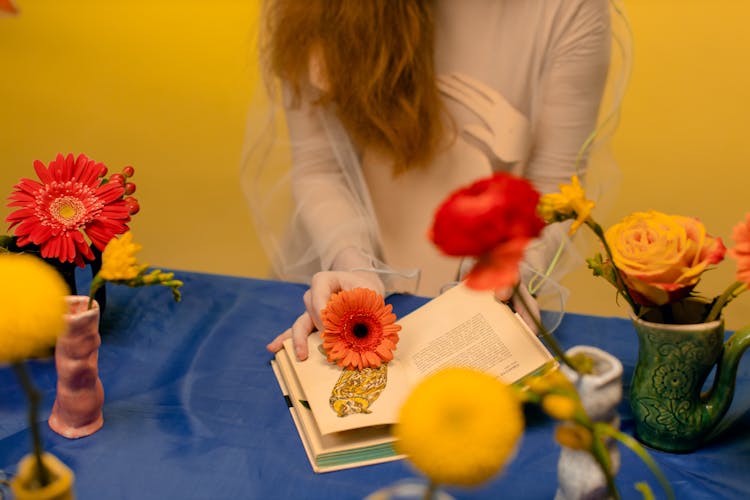 A Person Holding A Flower On A Book