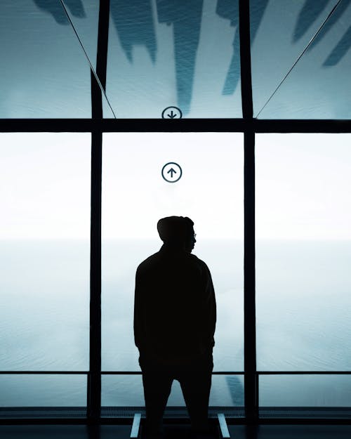 A Silhouette of a Person in Front of Glass Windows