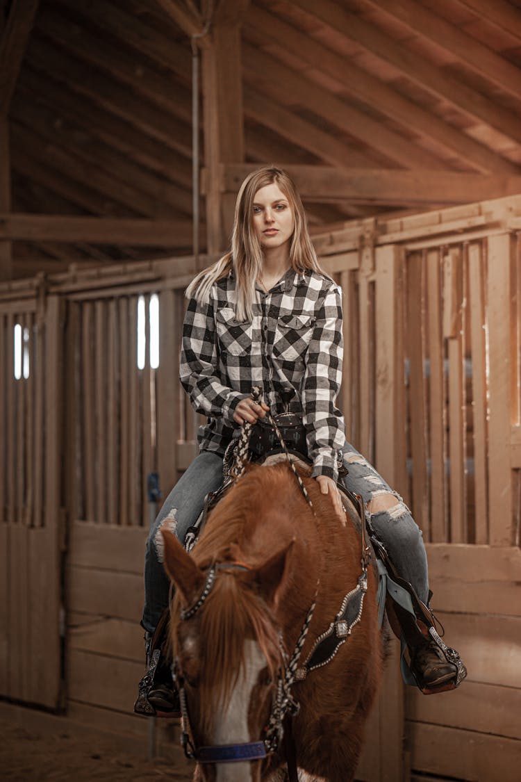 A Beautiful Woman Riding A Horse In A Stable