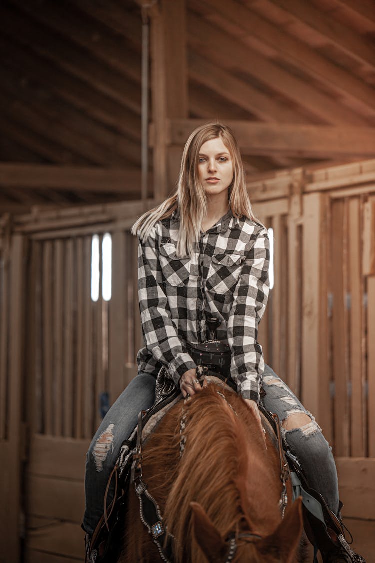 A Beautiful Woman Riding A Horse In A Stable