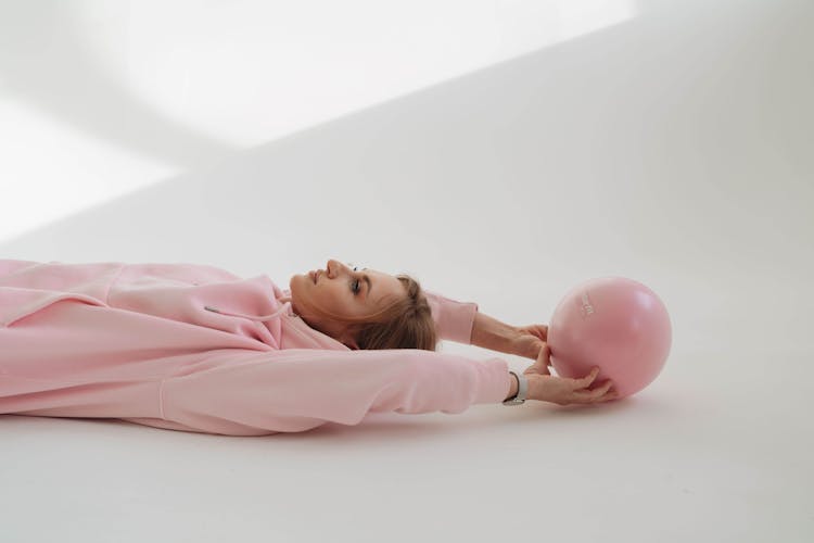 Woman Lying On Floor With Fitness Ball