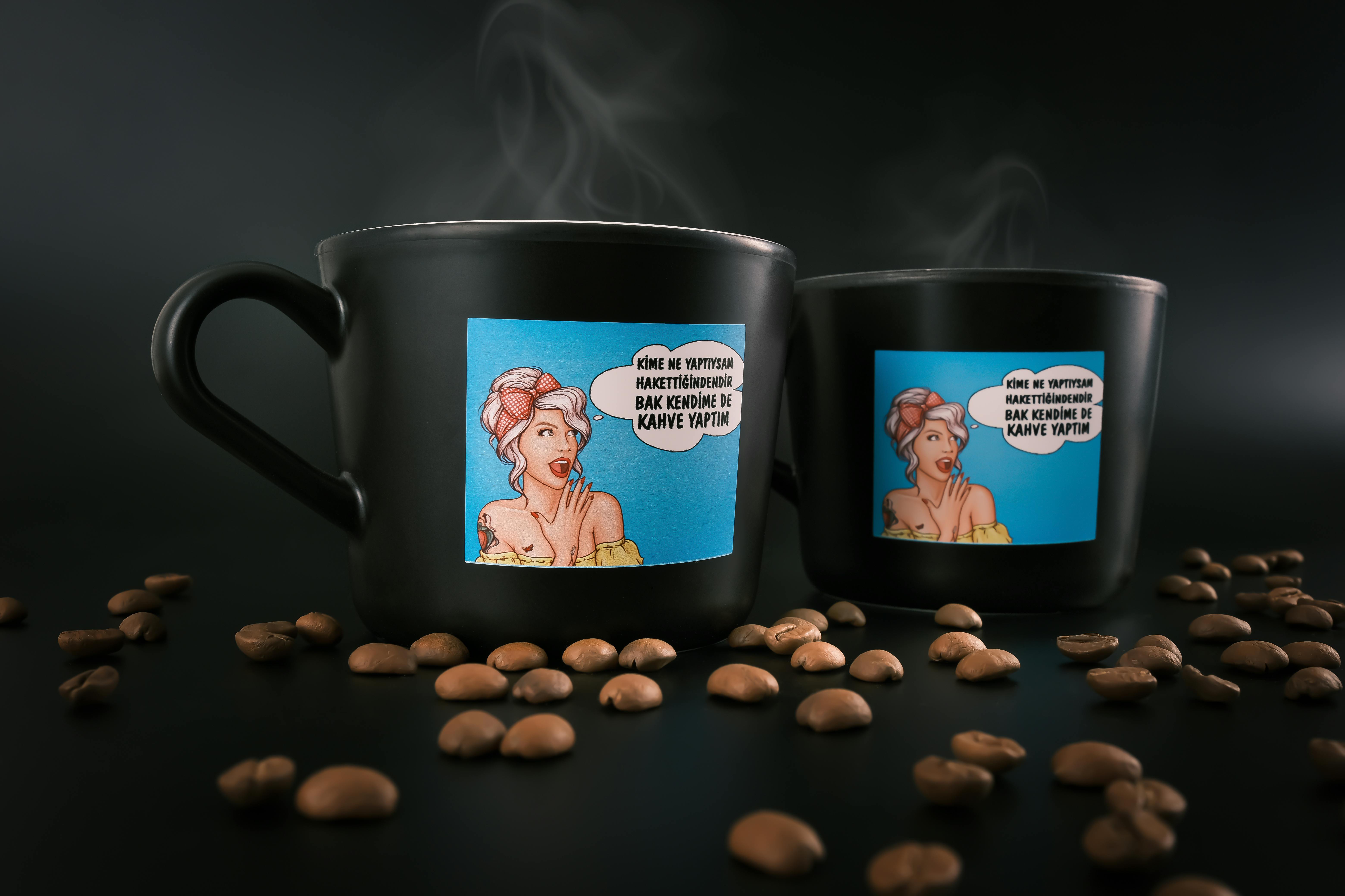 Black coffee mugs with a vibrant cartoon design surrounded by coffee beans. Perfect for coffee lovers.