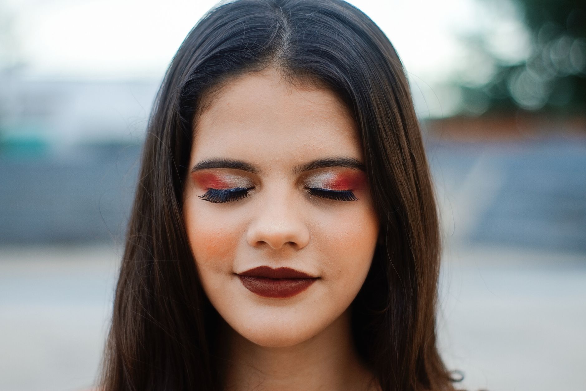 Close-up portrait of a woman with vibrant red and blue eye shadow and bold lipstick.