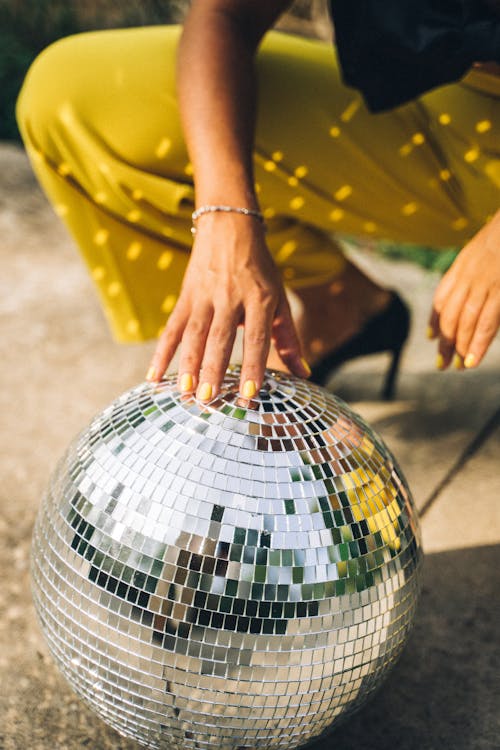 Person Resting Hand on Mirror Ball