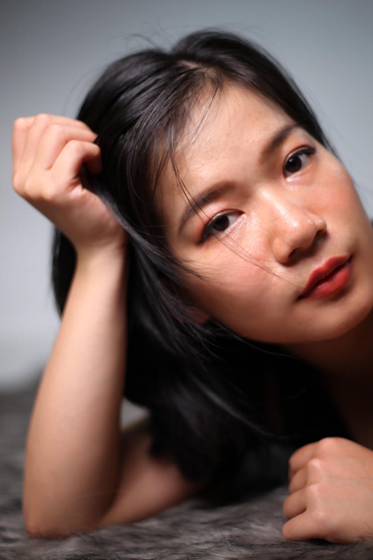 Calm Asian Woman Leaning Head On Hand On Soft Blanket