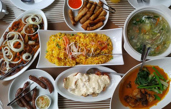 A vibrant top view of assorted Asian dishes including fried rice, spring rolls, and soup, showcasing a delicious culinary spread.