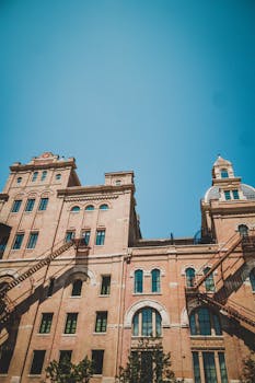 Low angle view of a historic brewery building facade under a clear blue sky in San Antonio, Texas. by Fabio Lima